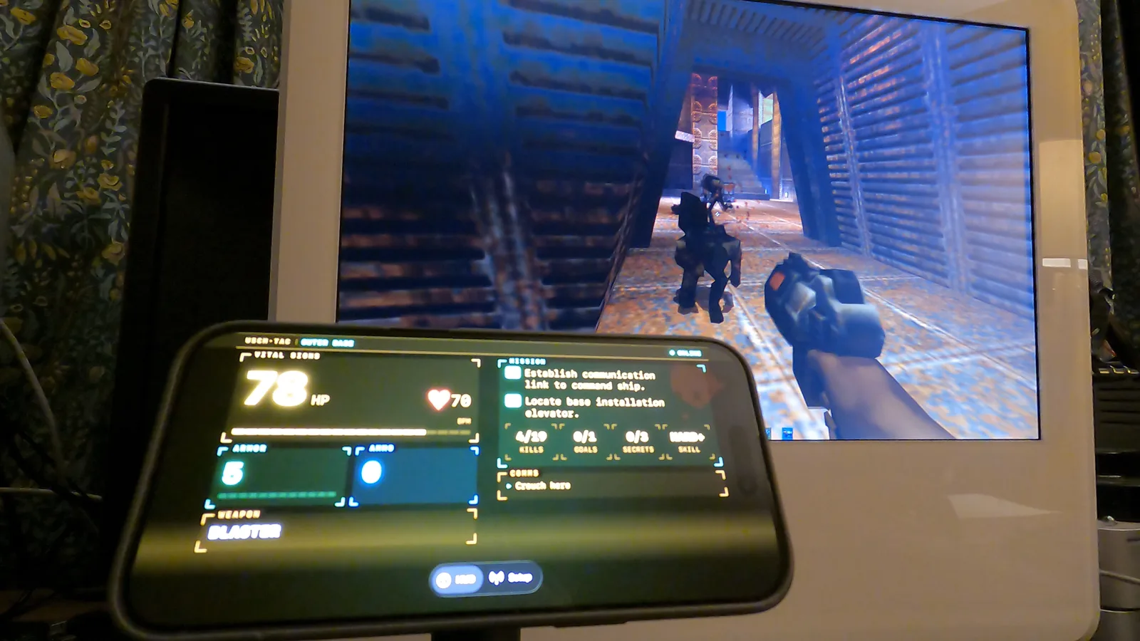 The iMac with a Strogg enemy on screen and the iPhone tactical computer HUD reading 78 HP alongside
